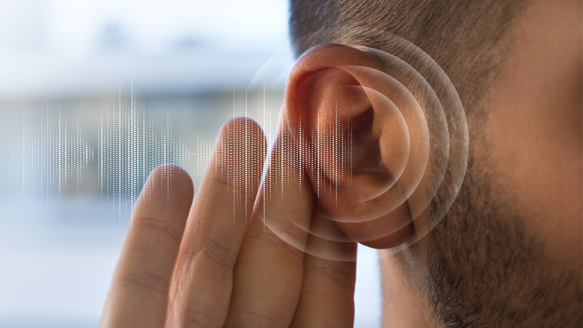 un homme tend son oreille pour mieux entendre